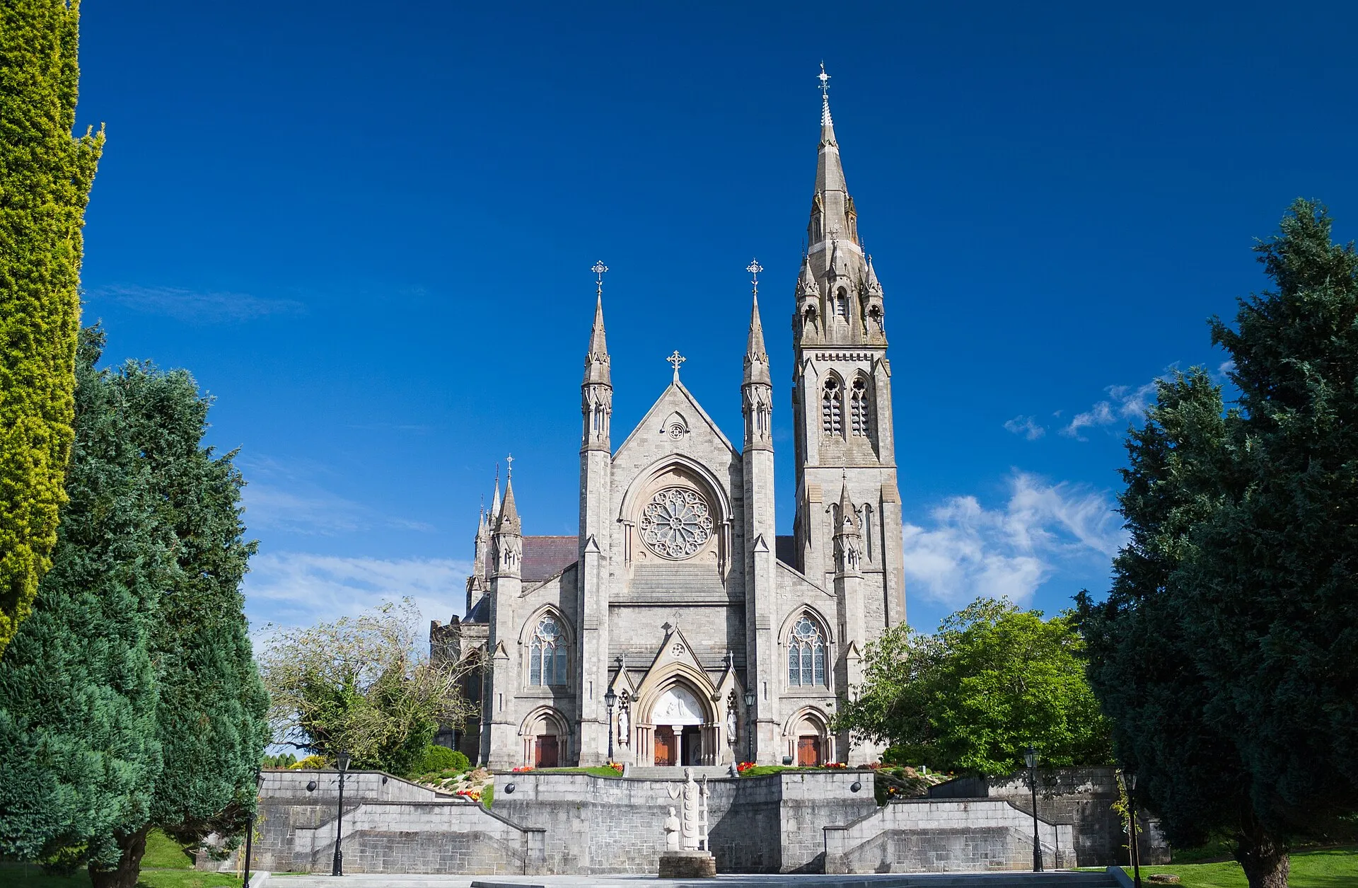 St Macartan's Cathedral, a neo gothic limestone cathedral with a tall spire, standing on high ground.